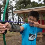 boy smiling while holding archery bow