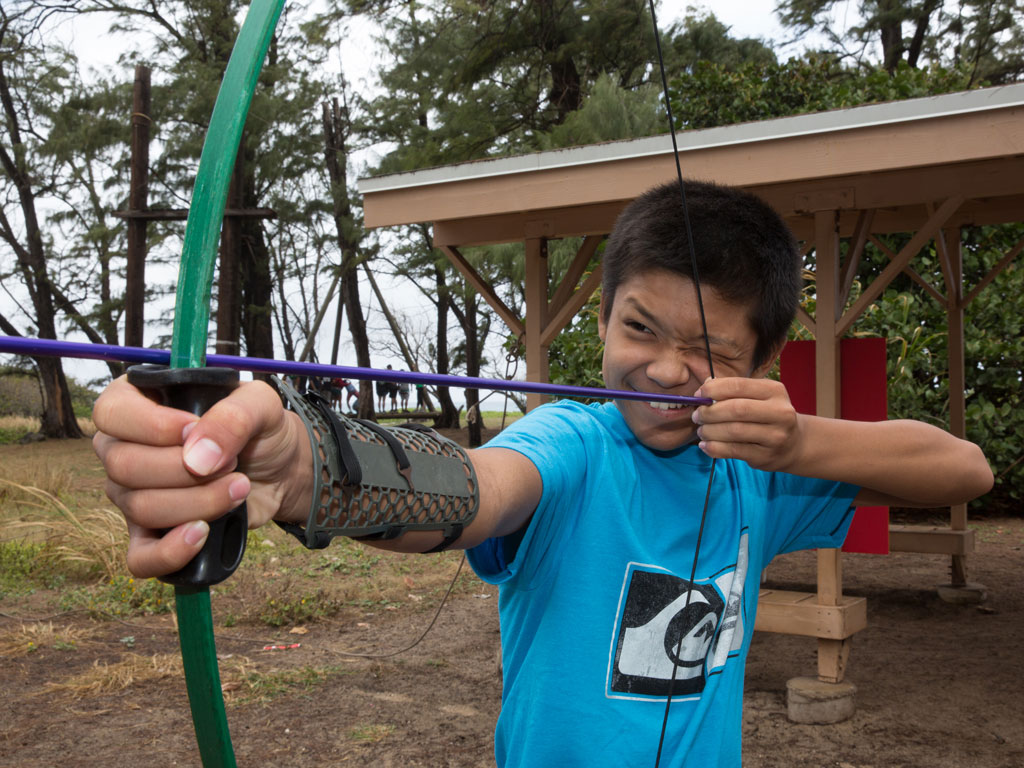 boy smiling while holding archery bow