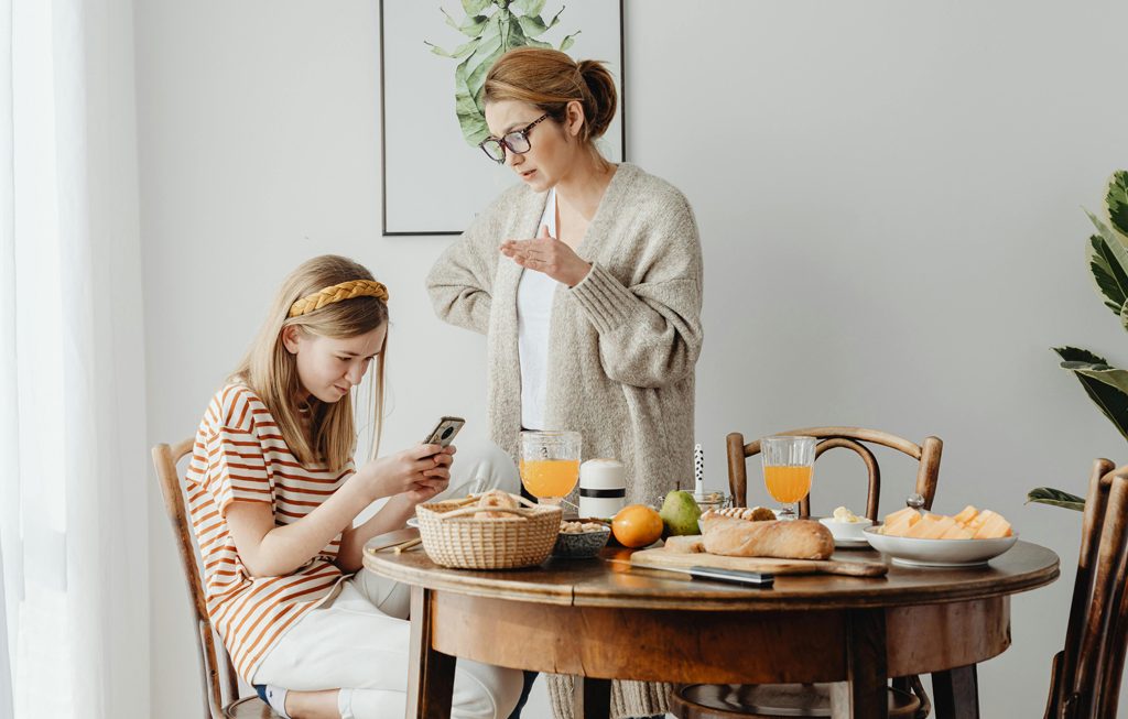 mom trying to talk to her teenage daughter who is on her smartphone