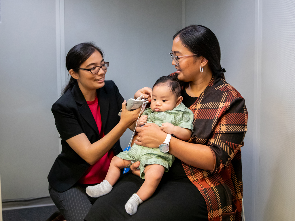 doctor performing a check up on an infant sitting on mom's lap