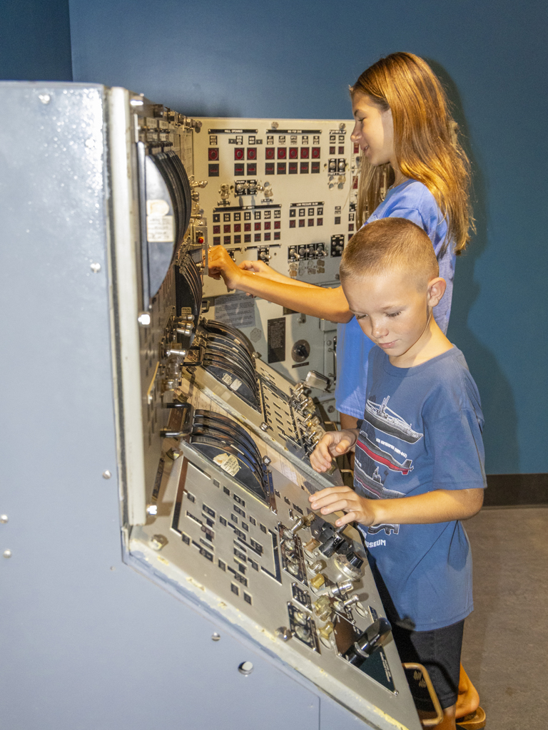 two youths interacting with a display at the Pacific Fleet Submarine Museum