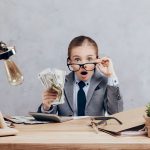 child in a suit with a handful of cash