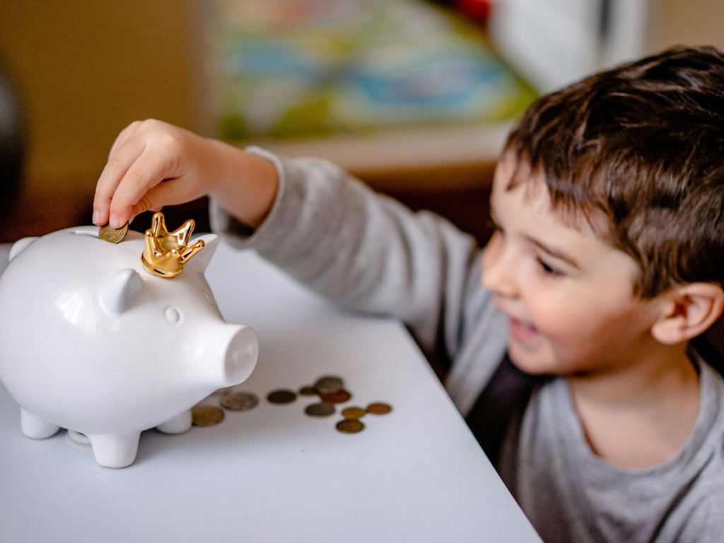 child putting coins in a piggy bank