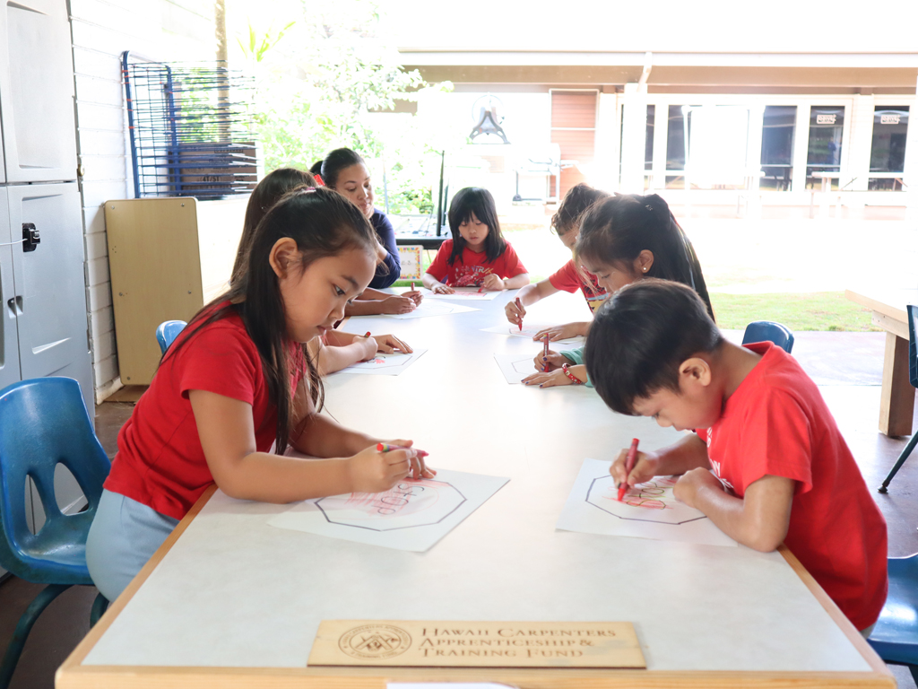 Rainbow Schools students coloring on donated tables