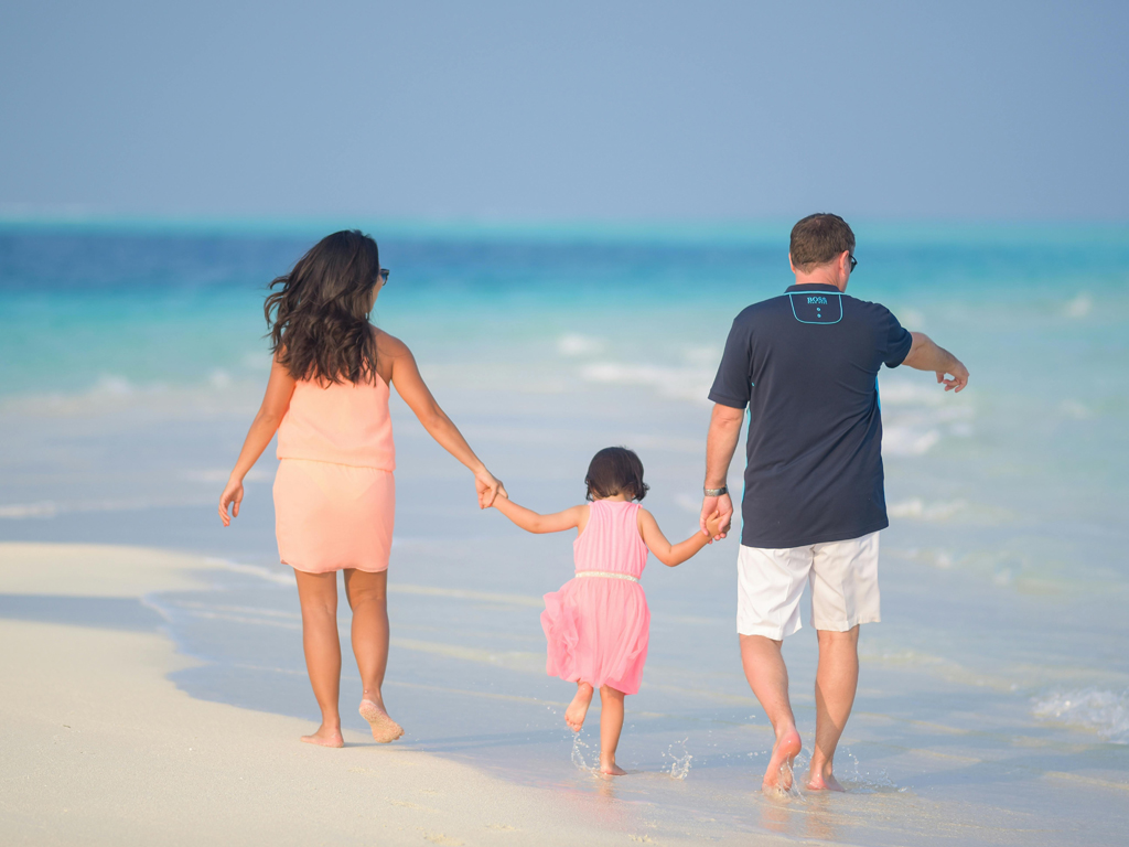 parents walking on the beach with their daughter