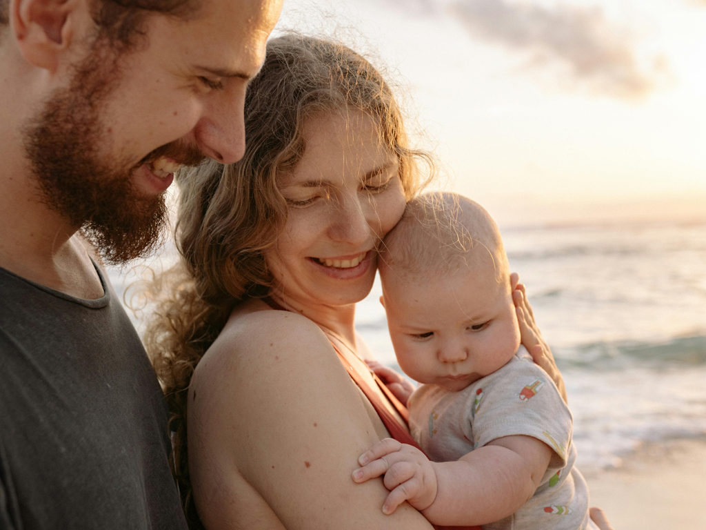 parents holding their baby at the beach