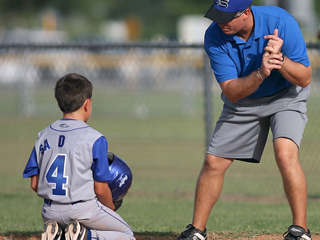 boy learning baseball tips from his coach
