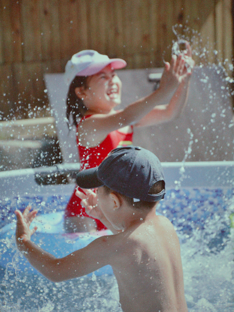 two kids splashing in a swimming pool
