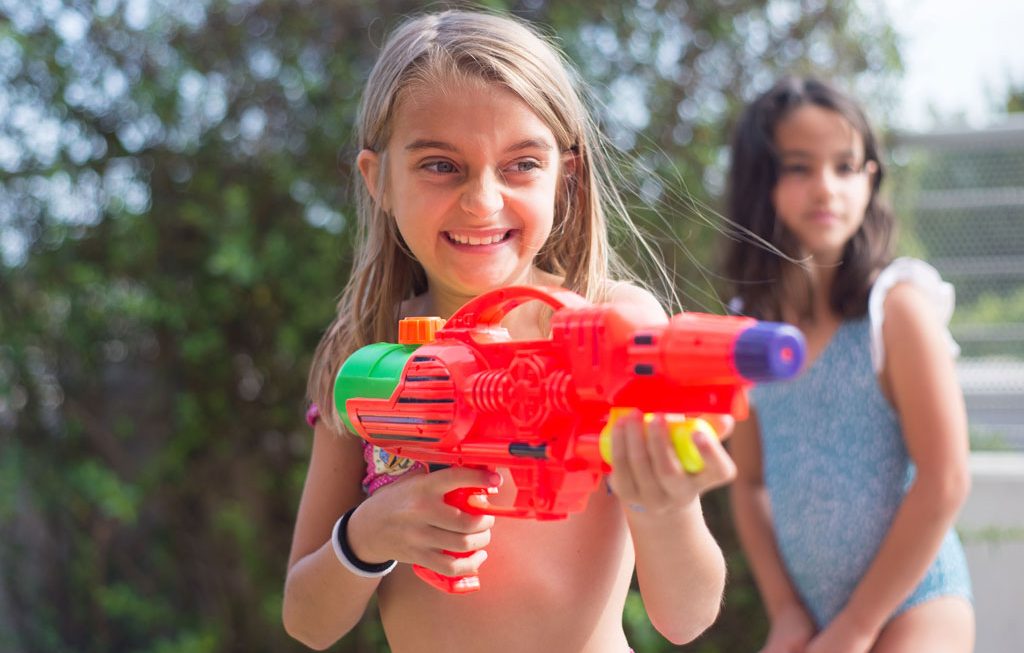girl smiling while holding a water gun
