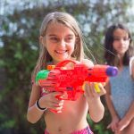 girl smiling while holding a water gun