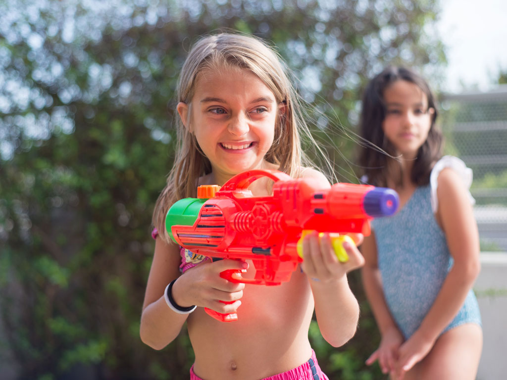 girl smiling while holding a water gun