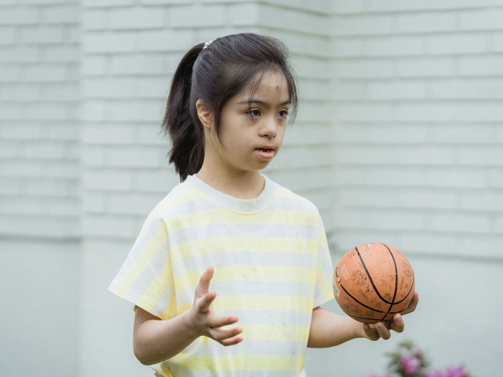 girl with down syndrome holding a small basketball
