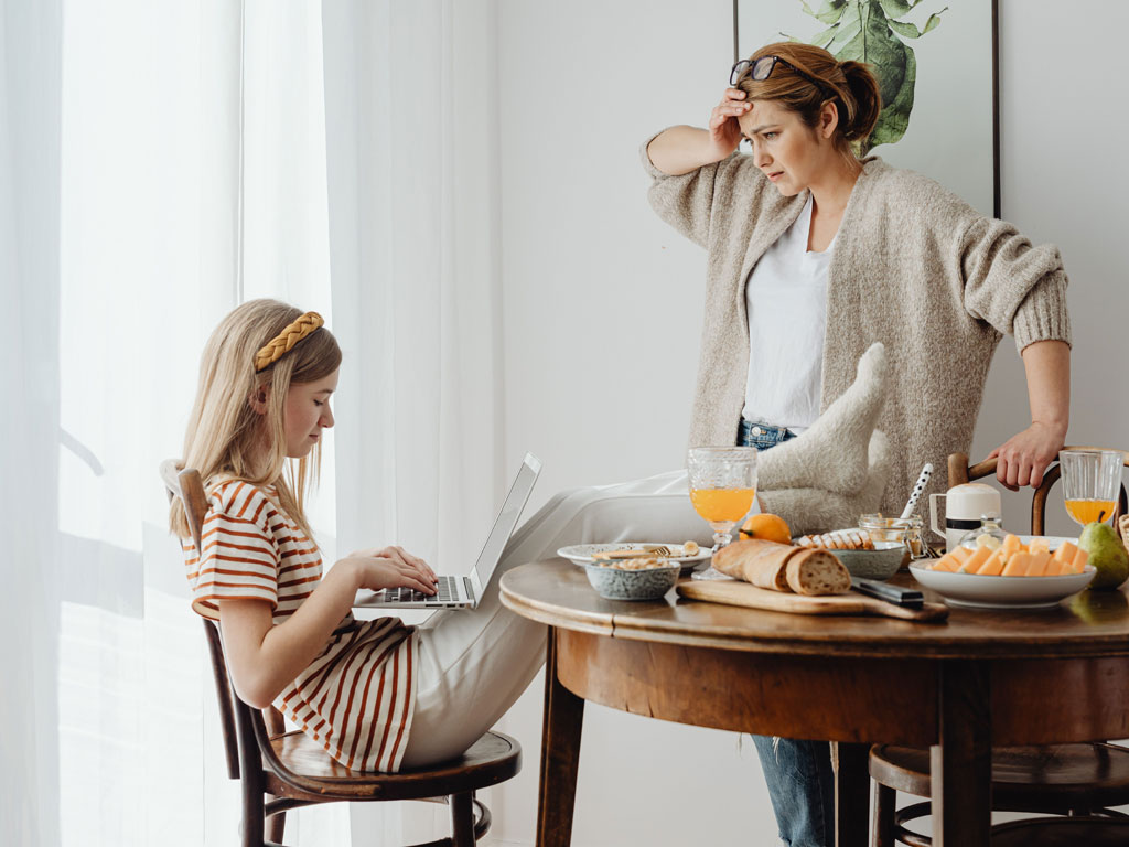 mom stressed as her daughter is has legs on dining table