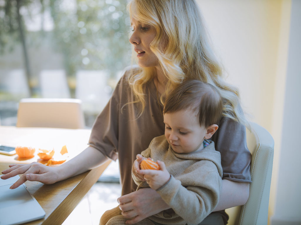 mom on her laptop while caring for son in her lap