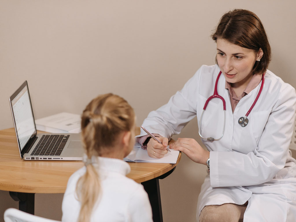 child speaking with her pediatrician