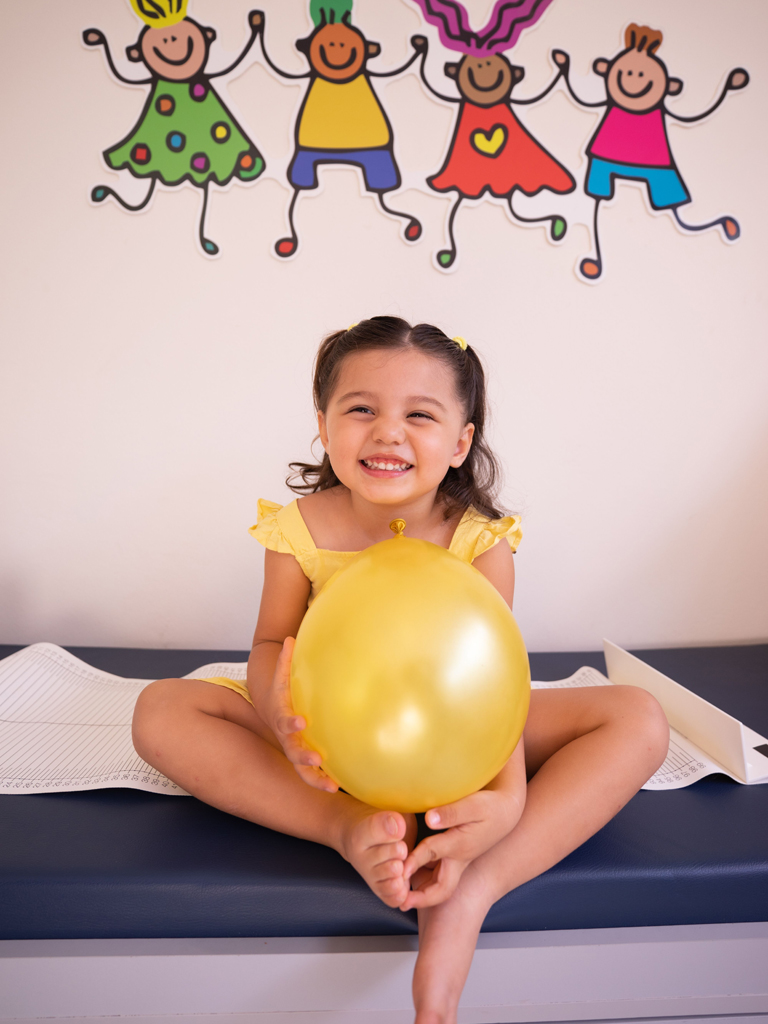 girl holding a balloon and smiling at the pediatrician's office